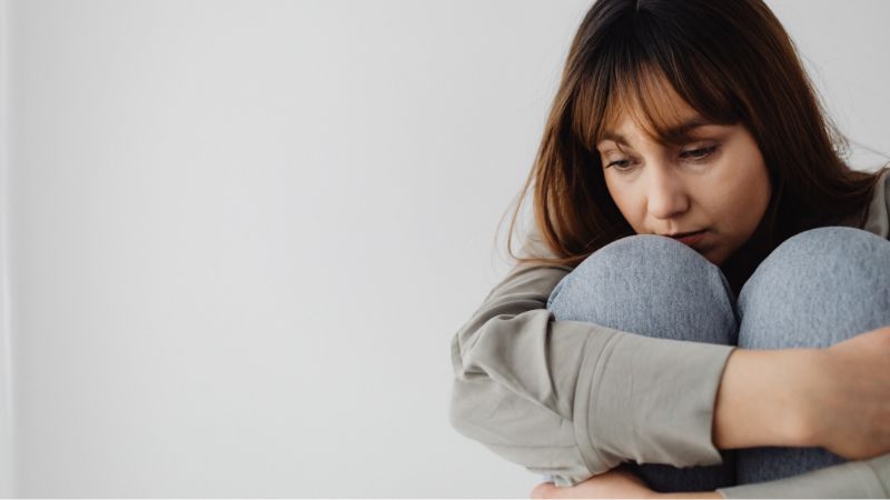 mulher encolhida abracando as pernas
